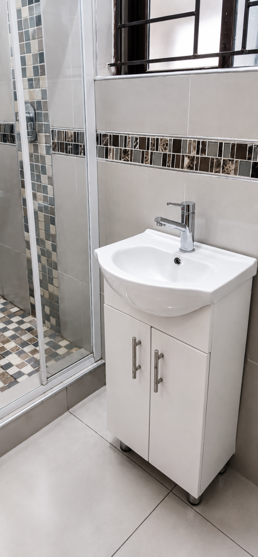 Clean modern bathroom with a glass walk-in shower and tiled walls
