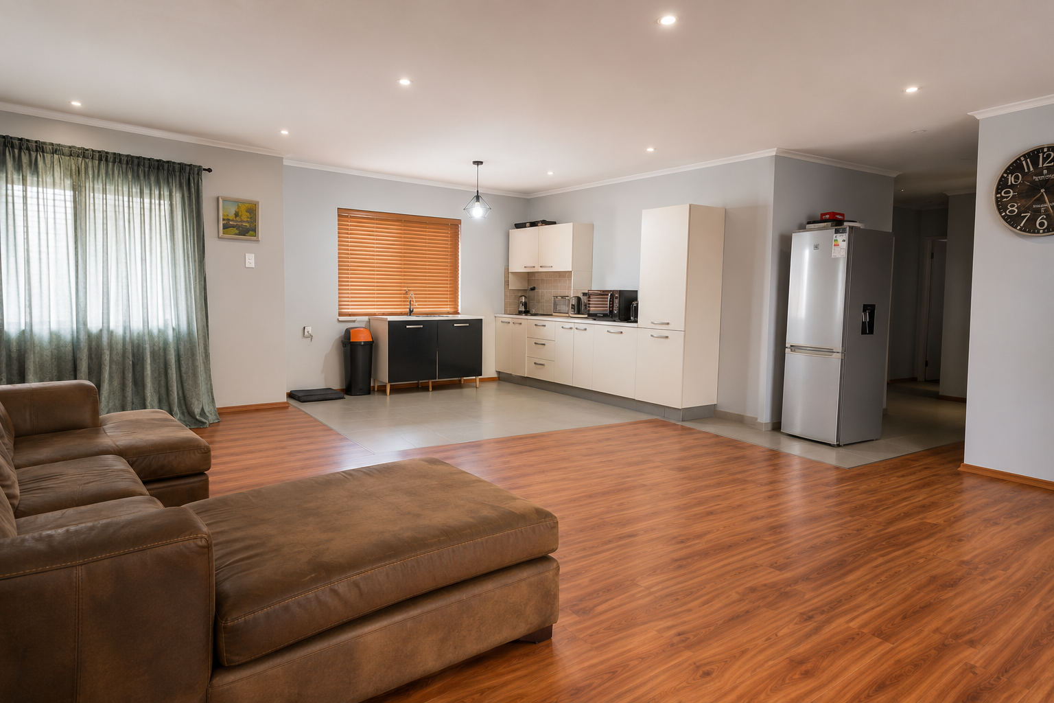 Spacious living area with a brown leather sofa and open kitchen